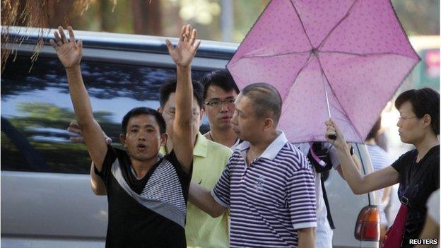 A petitioner (left) raises his hands as he is taken away by plainclothes policemen outside a court where the trial of Chinese rights activist Guo Feixiong is taking place in Guangzhou, Guangdong province, 12 September 2014.