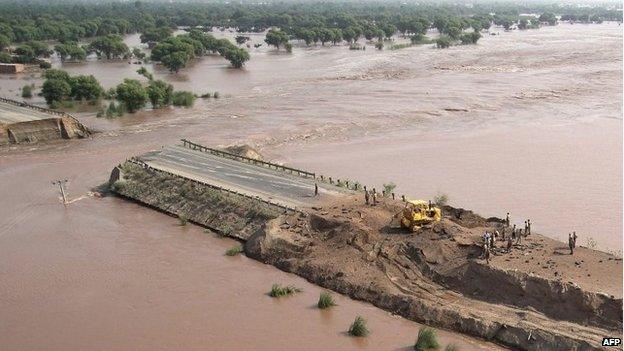 Pakistani soldiers stand on a dyke after it was breached to divert flood waters