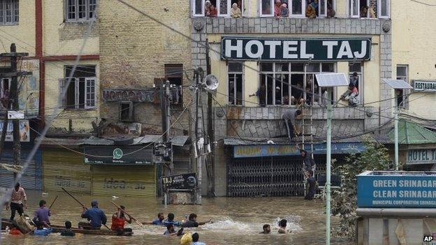 Flood victims watch from the windows of a hotel as Kashmiri volunteers try to get relief material to them 12 September