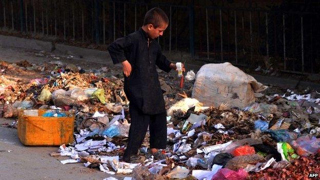 An Afghan child labourer collects cardboard and other materials from a rubbish heap on the outskirts of Jalalabad on August 8, 2014.