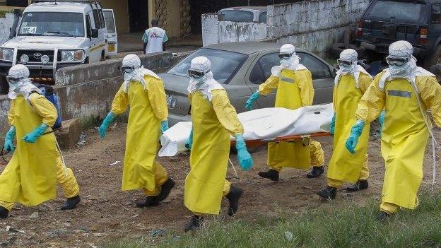 Liberian health care workers on an Ebola burial team collect the body of an Ebola victim at a motor vehicle garage in Paynesville on the outskirts of Monrovia, Liberia, 9 September 2014