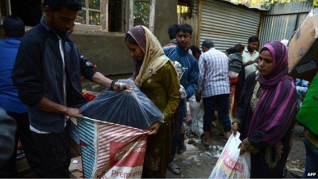 Kashmiri residents receive relief distributed by kashmiri volunteers in Rakshalana south of Srinagar on September 15, 2014