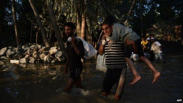 Kashmiri residents wade through floodwaters in Rakshalana, south of Srinagar, on September 15, 2014.