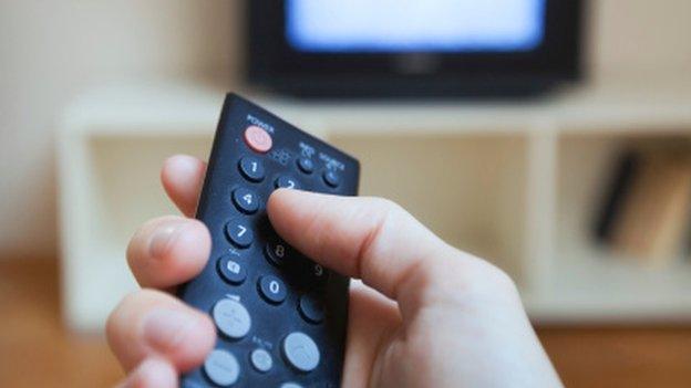 A person pressing a button on a television remote