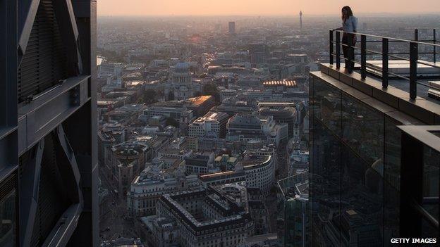 A woman looks out at the London skyline from an upper floor of a newly constructed skyscraper, The Leadenhall Building, as the sun sets on September 9, 2014