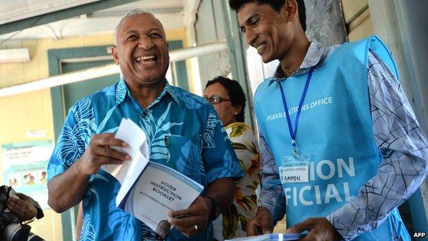 Fijian military strongman Voreqe Bainimarama (left) shares a light moment with an election official before casting his election vote at the Vatuwaqa Public School in the capital Suva on 17 September, 2014