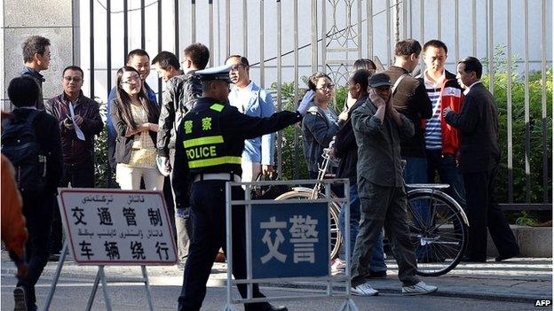 A Chinese policeman tries to control the crowd waiting to be allowed to enter the Urumqi Intermediate People's court as the trial of Ilham Tohti, a former economics professor at a university in Beijing, begins in Urumqi, west China's Xinjiang region on 17 September 2014