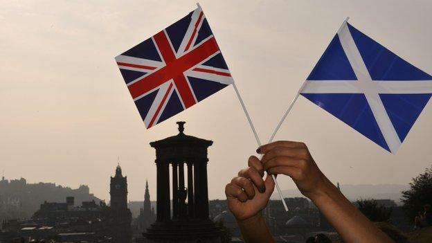 A union flag and saltire held up in front of the Edinburgh