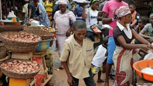 Locals walk in a market in Kenema, Sierra Leone, on 16 August 2014