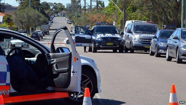 Police and other law enforcement agencies cordon off a street as forensic experts collect evidence inside a house in the Guildford area of Sydney (18 September 2014)