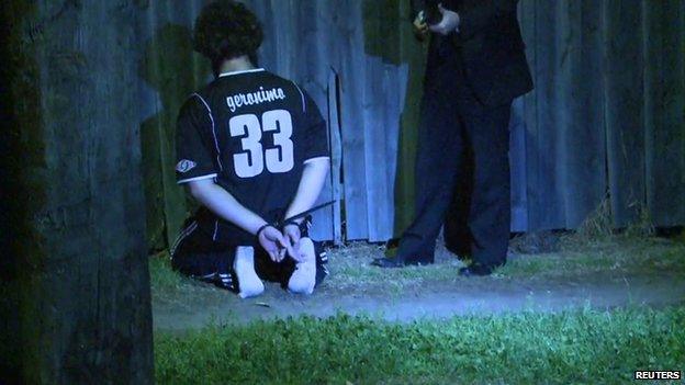 A man detained by police during a raid kneels on the ground in Sydney, in this still image taken from police handout video 18 September 2014