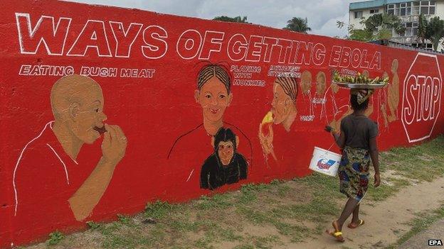 Liberian woman walks past a wall mural about the Ebola virus in Monrovia
