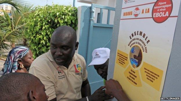 Senegalese health worker posts an Ebola prevention poster during an Ebola awareness campaign in a suburb of Dakar