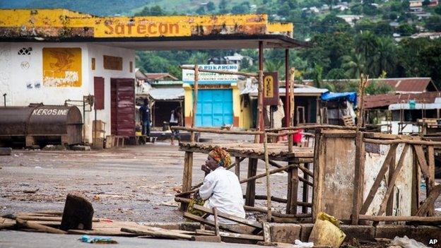 A trader sits at an empty local market area in Waterloo, Sierra Leone, 19 September 2014