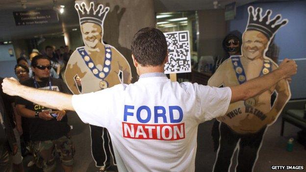 A supporter of Rob Ford stands in front of two cardboard cutouts of the Toronto Mayor