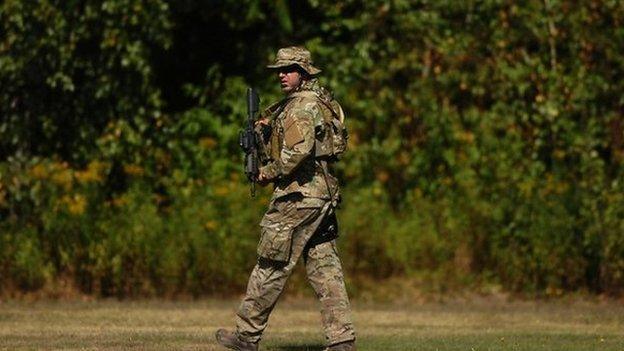 A Pennsylvania State Trooper prepares to enter a wooded area at the Dunmore Cemetery during the funeral service of Pennsylvania State Trooper Bryon Dickson in Dunmore, Pennsylvania 18 September 2014