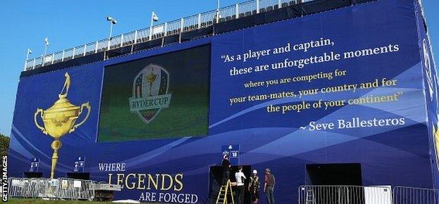 A group of workmen prepare a giant image on the back of one of the main grandstands at Gleneagles