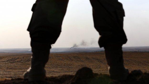 An Iraqi Kurdish Peshmerga fighter holds a position as smoke billows on the front line in Khazer, 40 km West of Irbil, in northern Iraq on 16 September 2014.