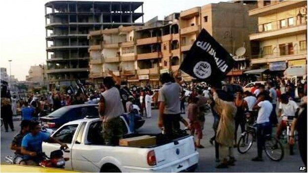 In this undated file photo posted on Monday, June 30, 2014 by the Raqqa Media Center of the Islamic State group, a militant extremist group, which has been verified and is consistent with other AP reporting, fighters from extremist Islamic State group parade in Raqqa, Syria