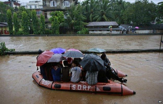 State Disaster Response Force personnel rescue people on a boat in a flooded area during heavy monsoon rains in Gauhati, Assam state, India, Monday, Sept. 22, 2014.