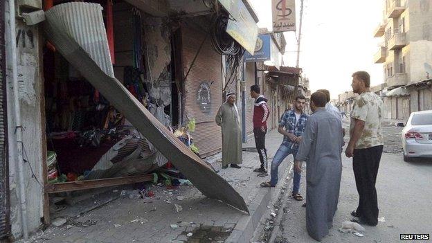 People inspect a shop damaged after what Islamist State militants say was a US drone crash in Raqqa - 23 September 2014