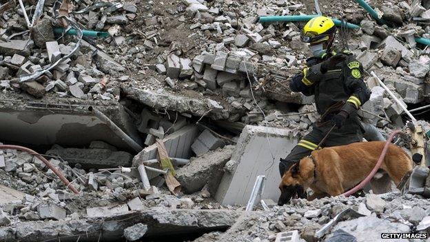 Rescuers look for victims in the rubble, following the 12 October collapse of a building in Medellin on 21 October, 2013.