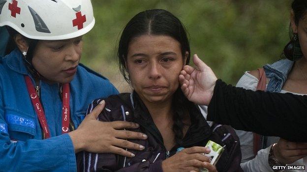 In this 18 October 2013 photo a member of the Red Cross comforts relatives of people who are still missing following the collapse of Tower 6 of the Space apartment complex