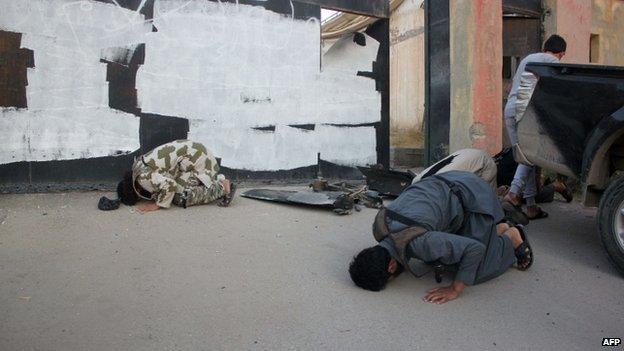 Fighters from the Islamic State (IS) organisation pray at the spot where the jihadist group said a US drone crashed into a communications tower in the Syrian city of Raqqa early on 23 September 2014.