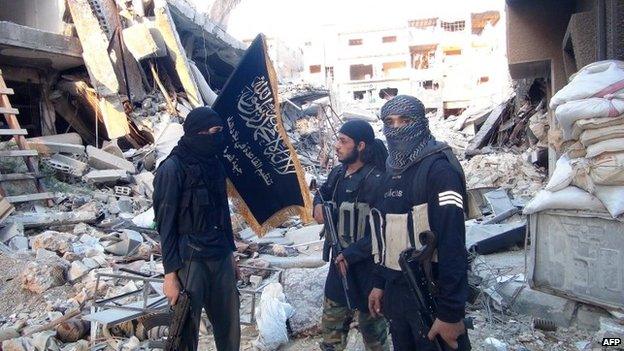 Al-Nusra Front fighters stand among destroyed buildings in the Yarmouk Palestinian refugee camp in southern Damascus (22 September 2014)