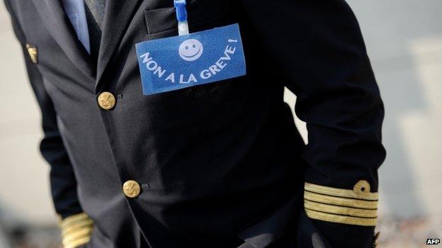 An Air France pilot wears a badge reading "No to the strike" during a demonstration against the French airline pilots' strike