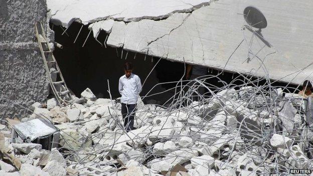 A resident walks upon the debris of buildings which were damaged in what activists say was one of Tuesday's US air strikes in Kfredrian, Idlib province, 24 September 2014