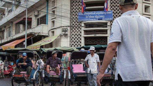 A group of cyclo drivers wait for customers in front of one of the street markets in the city centre on 13 August 2014 in Phnom Penh, Cambodia.