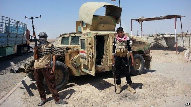 Islamic State militants stand at a checkpoint near the Baiji oil refinery in Iraq (19 June 2014)