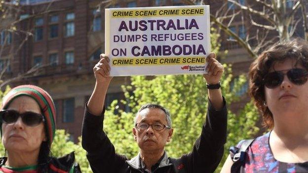 A protester holds up a placard at a rally in Sydney on 26 September 2014, opposing Australia's plan to start sending asylum-seekers to Cambodia by the end of the year.