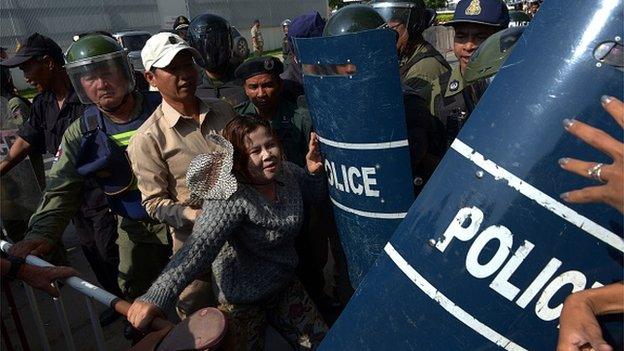 A Cambodian rights activist (C) clashes with police officials at a protest next to the Australian embassy in Phnom Penh