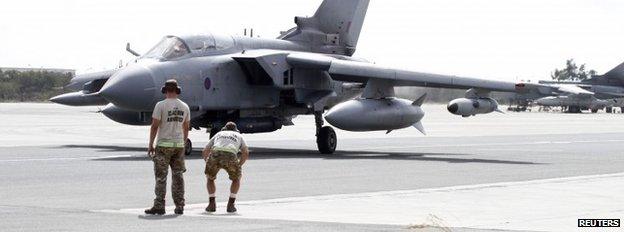 Servicemen stand near a Tornado jet as it prepares to take off