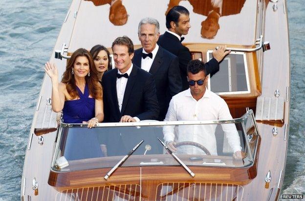 The model Cindy Crawford (L) waves from a boat on the Grand Canal, flanked by her husband, businessman Rande Gerber, 27 September