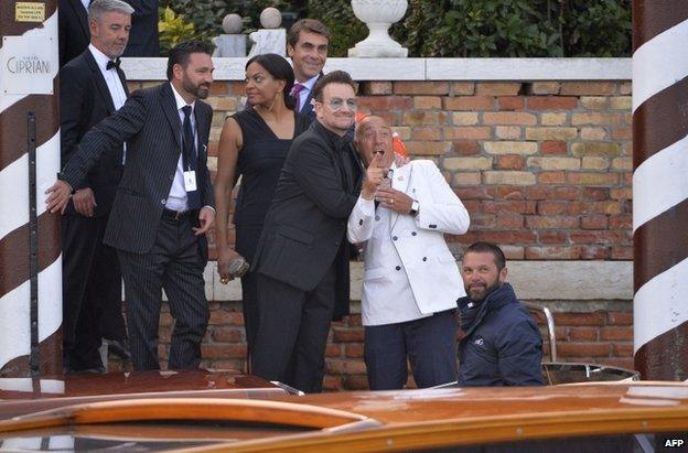 Bono (in dark glasses) jokes with a concierge as he boards a taxi boat in Venice, 27 September