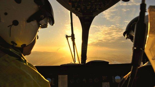 Pilots look out at setting sun while in flight