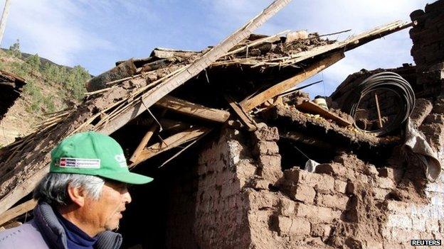 A man passes by the debris of a damaged house at a street in Paruro after the quake hit on 28 September, 2014.