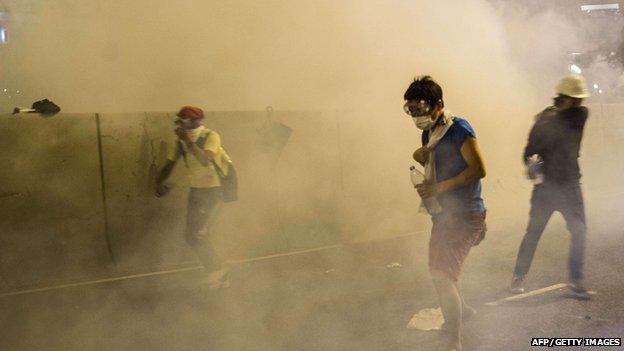 Protesters in face masks take refuge as police fire tear gas at a pro-democracy demonstration in Hong Kong