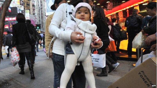 In a photo taken on 18 January 2012, a baby is carried by her mother in Hong Kong