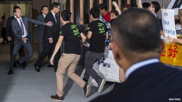 Students rush at CY Leung as he leaves his offices