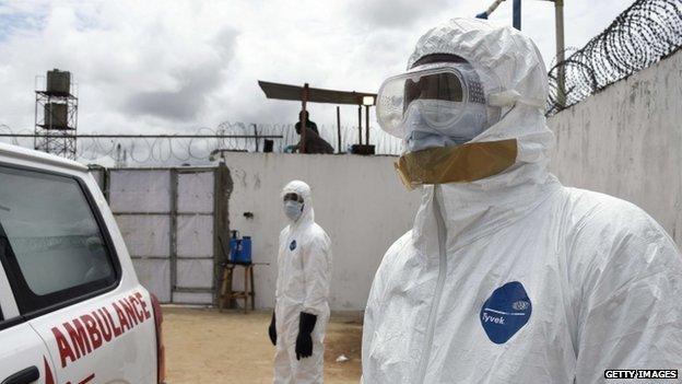 Health workers in protective suits look at an ambulance upon its arrival at Island Hospital in Monrovia on 30 September 2014