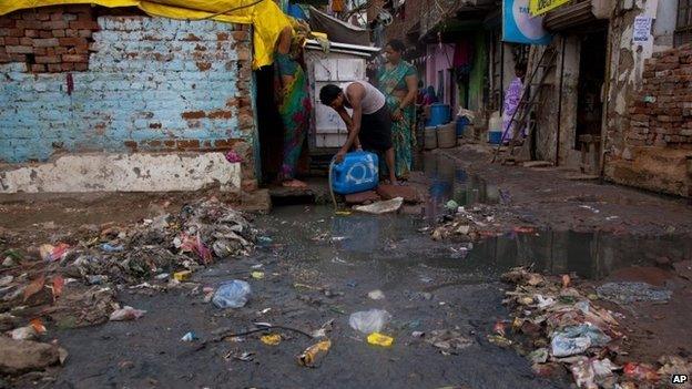 In this Thursday, Aug. 28, 2014 photo, a man fills drinking water from a tap covered by stagnant water and garbage in New Delhi, India