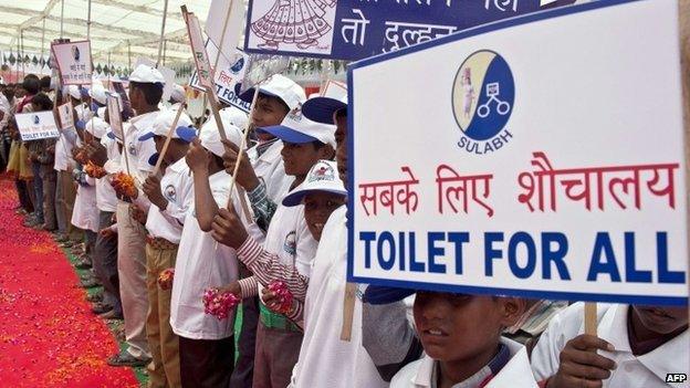 Indian schoolchildren hold placards as they welcome Bindeshwari Pathak, founder and chairman of NGO Sulabh International, at Katra Sahadatgunj village in Badaun on August 31, 2014