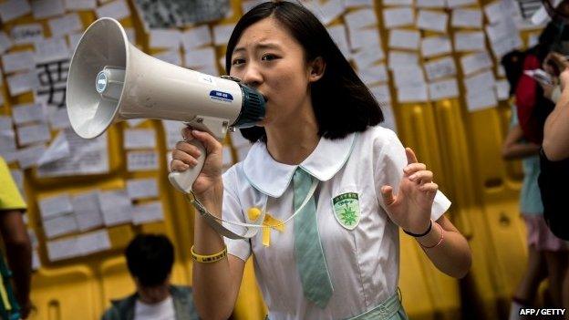 A schoolgirl in Hong Kong speaks to protesters using a megaphone on 1 Oct