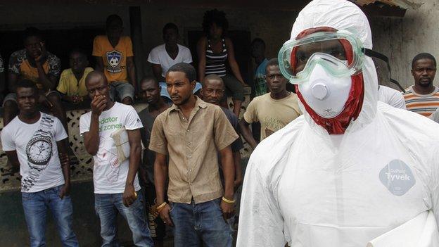 People watch as a burial team enters their community to collect a dead body suspected of being an Ebola victim in the slum area of Logan Town outside Monrovia