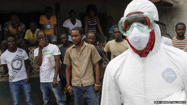 People watch as a burial team enters their community to collect a dead body suspected of being an Ebola victim in the slum area of Logan Town outside Monrovia