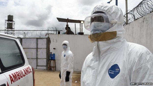 Health workers in protective suits look at an ambulance upon its arrival at Island Hospital in Monrovia on September 30